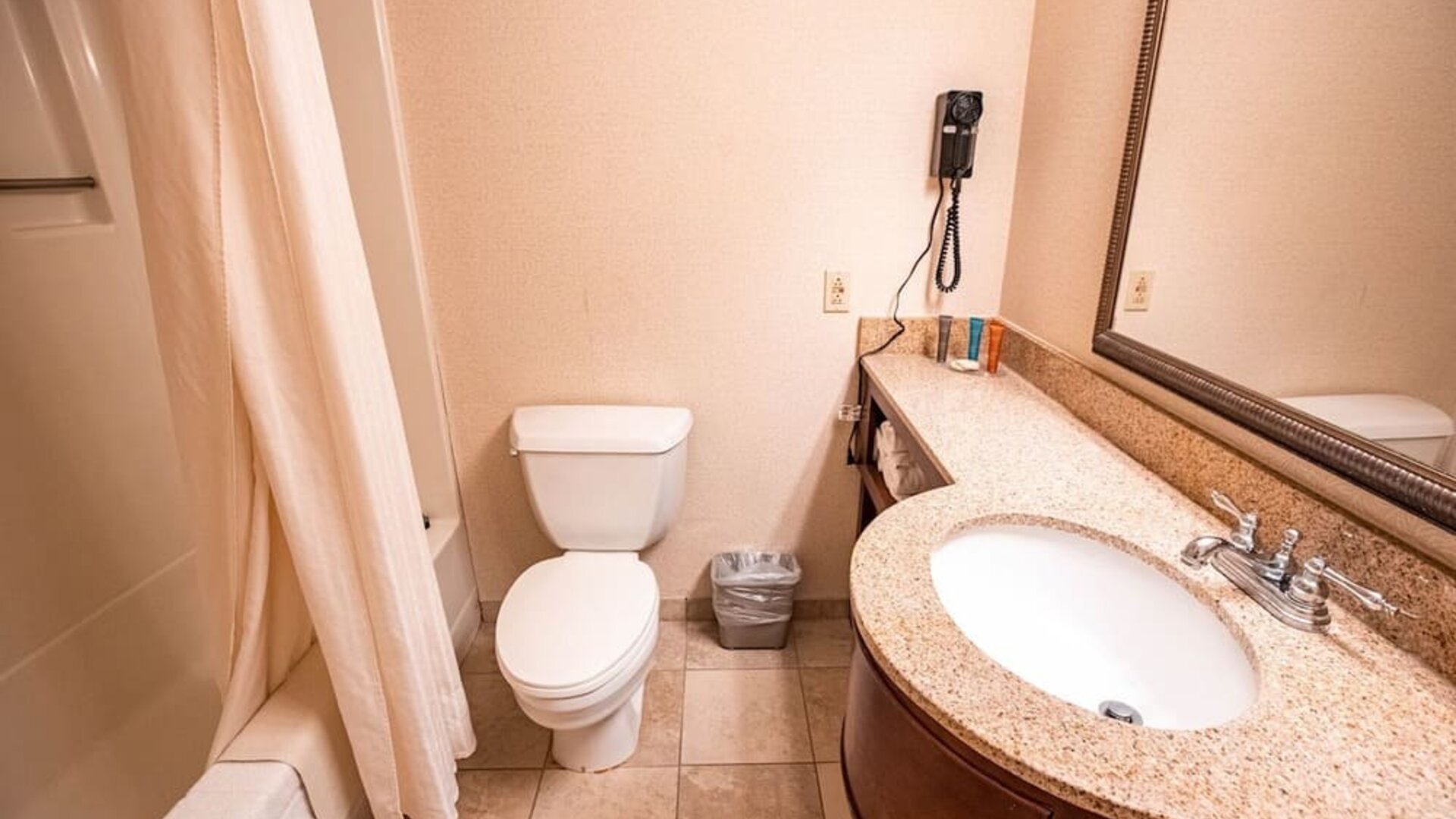 Guest bathroom featuring a granite countertop vanity, full bath, and essential amenities at Sturbridge Host Hotel.