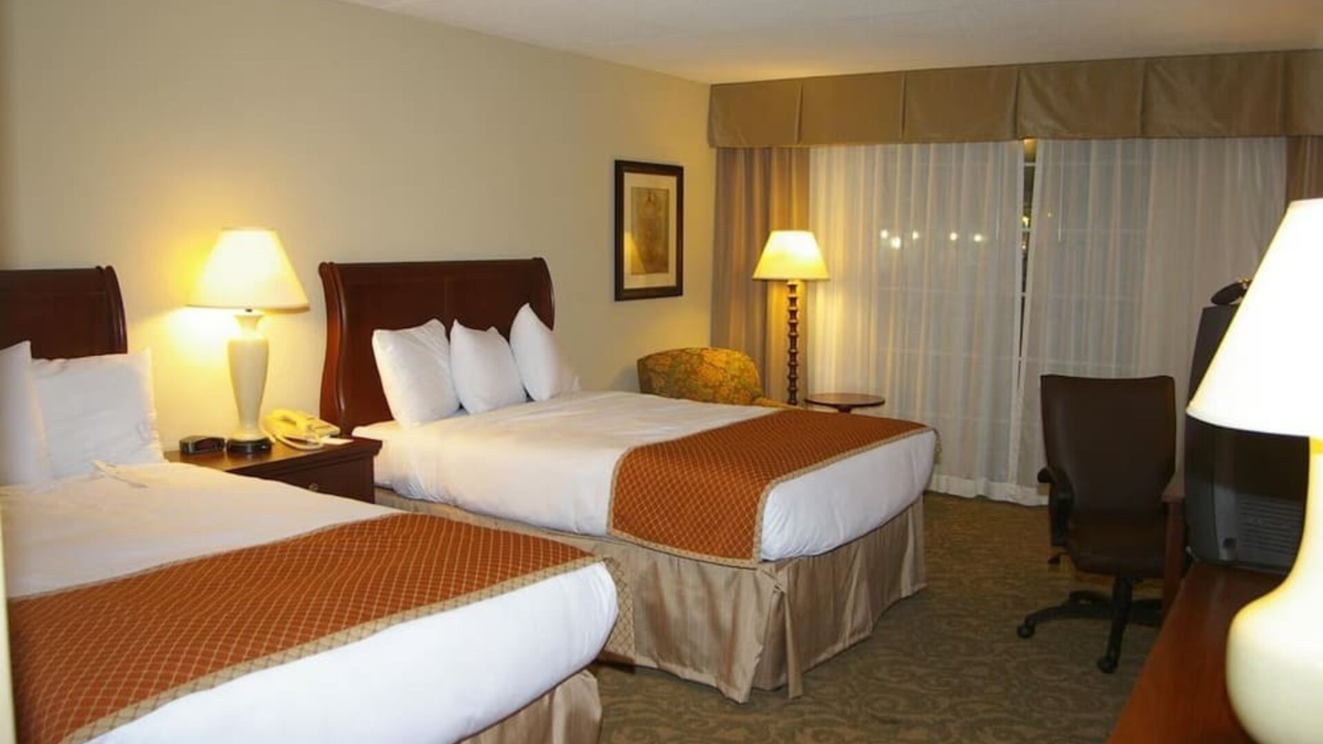 Double queen guest room with comfortable bedding, work area, and inviting accommodations for families or groups at Sturbridge Host Hotel.