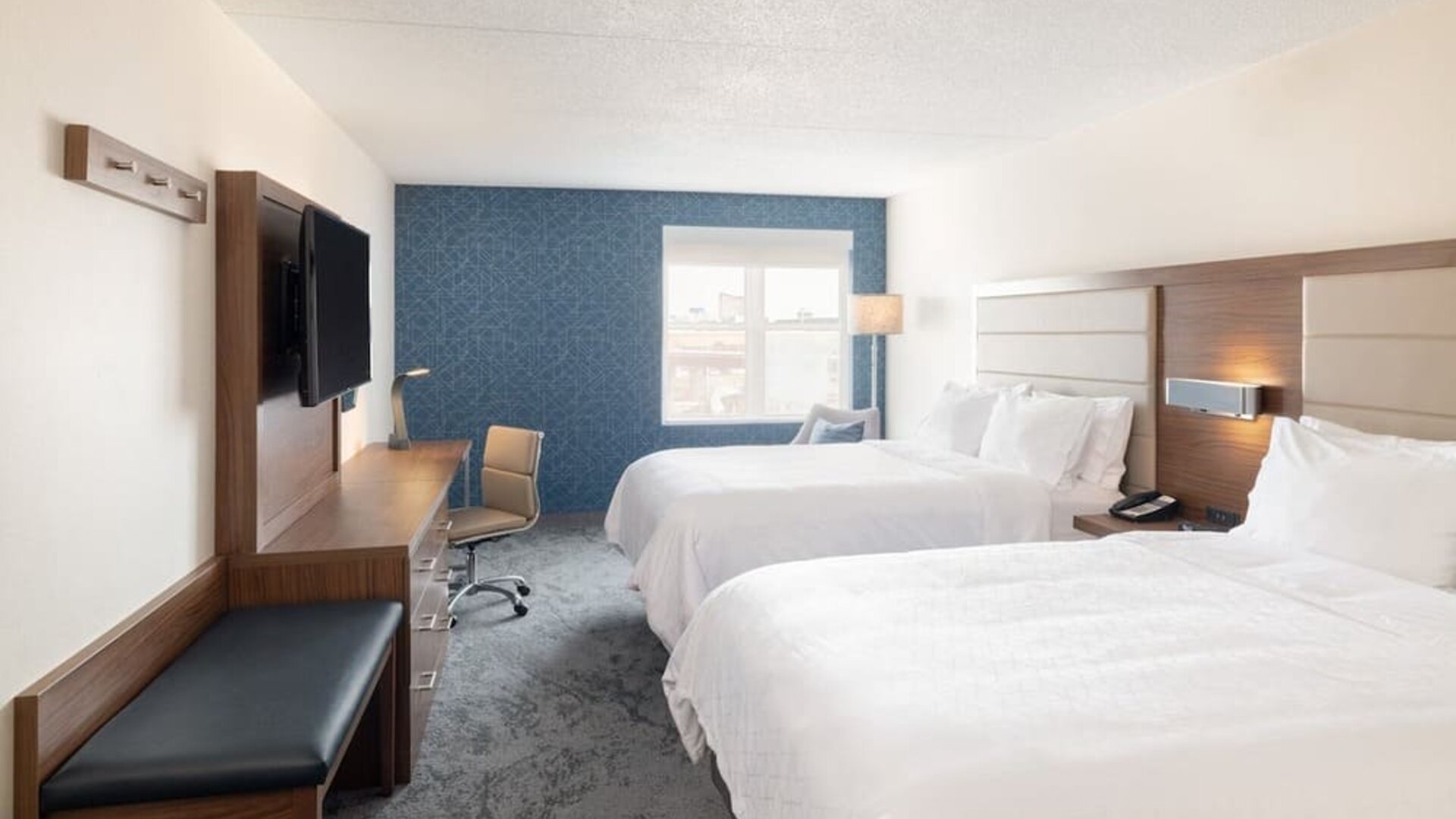 Double queen guest room with comfortable bedding, workspace, and contemporary décor designed for families and groups at Holiday Inn Express & Suites Boston-Cambridge.