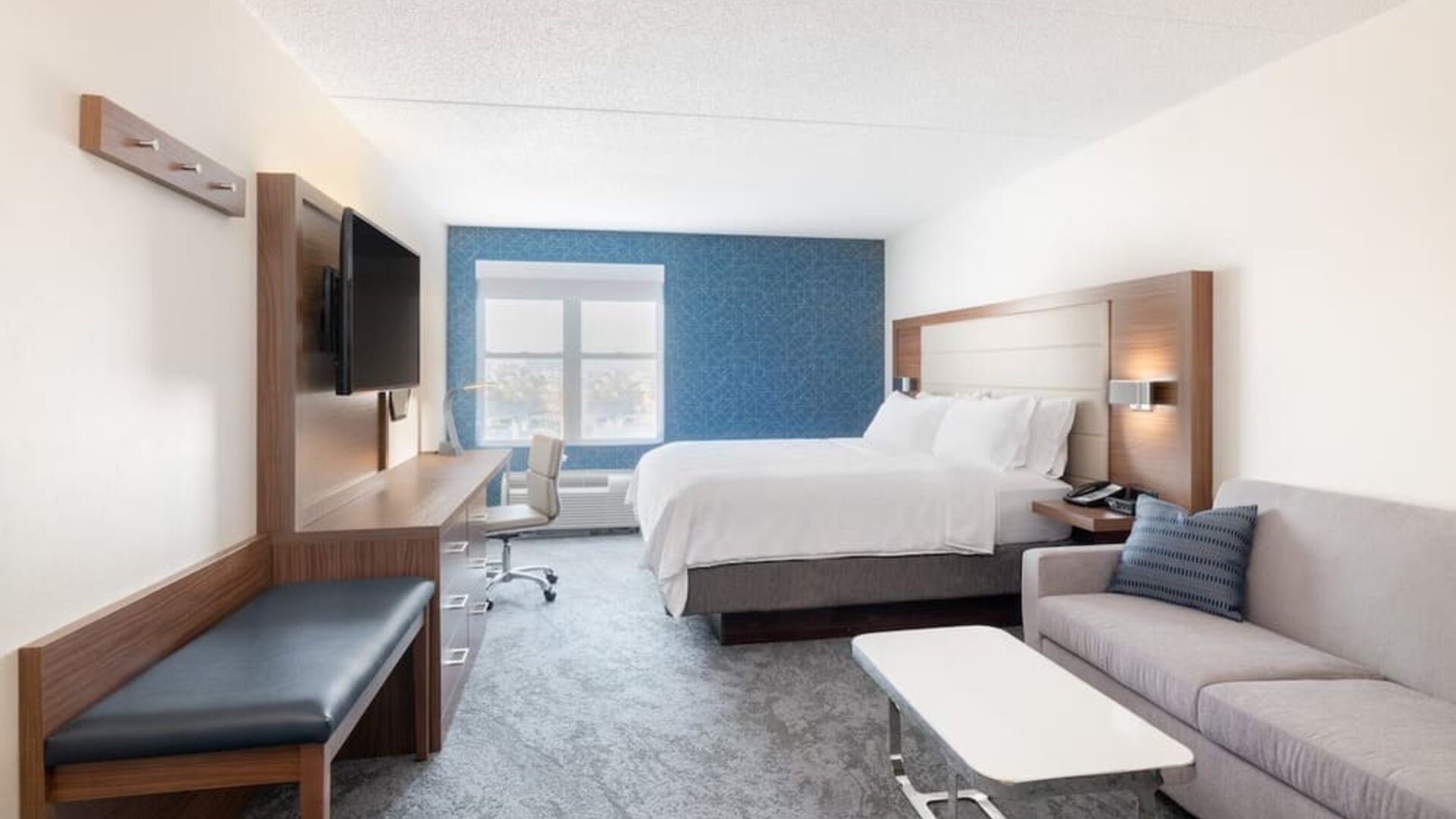 Bright guest room featuring a king bed, comfortable seating area, and abundant natural light at Holiday Inn Express & Suites Boston-Cambridge.