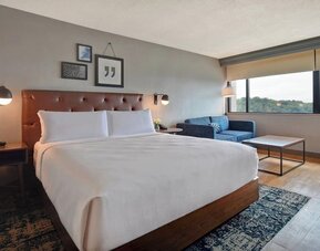 Contemporary king guest room offering plush bedding, comfortable seating, and expansive views through large picture windows at Four Points by Sheraton Boston-Newton.