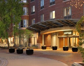Welcoming hotel entrance featuring covered access, landscaped surroundings, and convenient arrival accommodations at Courtyard by Marriott Boston Brookline.