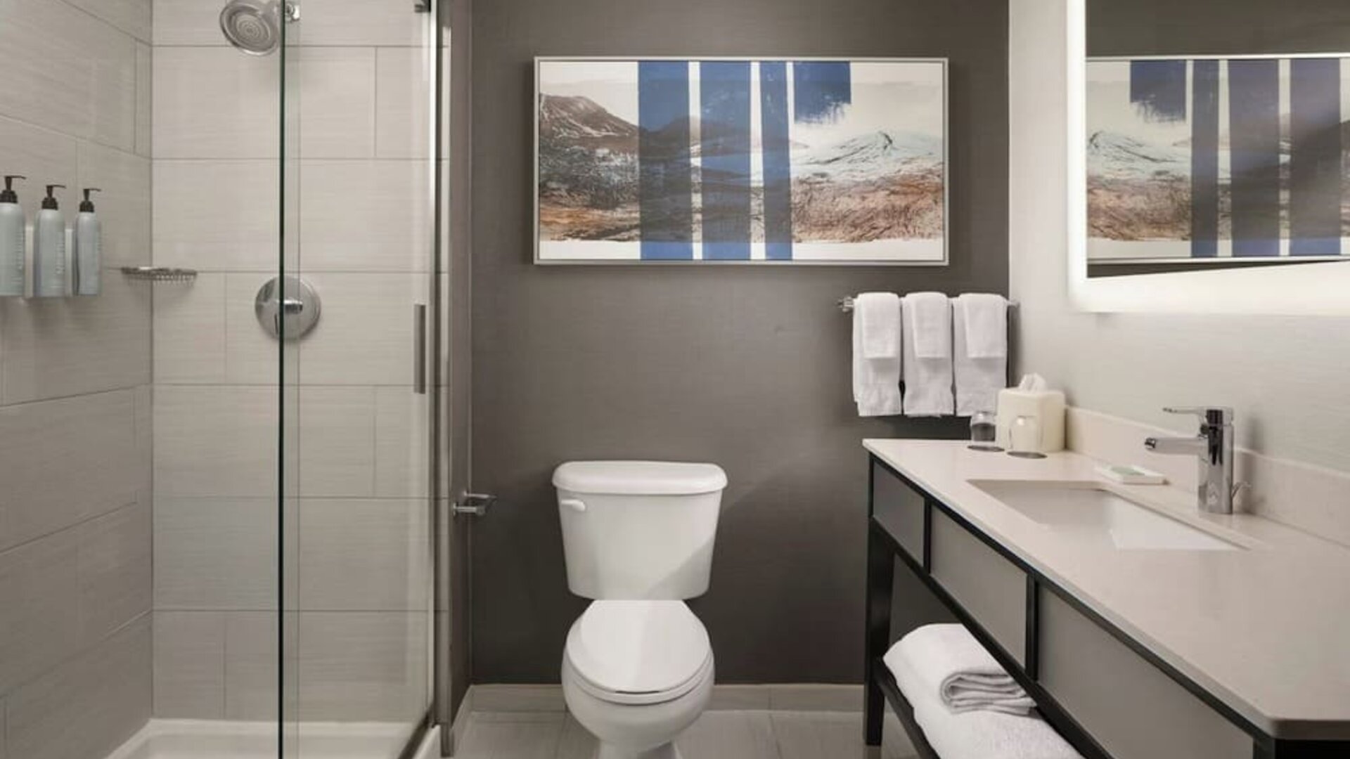 Modern guest bathroom featuring a spacious walk-in shower, illuminated mirror, premium amenities, and contemporary finishes at Courtyard by Marriott Boston Brookline.