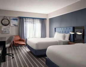 Double queen guest room offering comfortable accommodations, modern furnishings, and thoughtful amenities for families and groups at Courtyard by Marriott Boston Brookline.