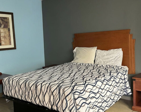 Guest room featuring a comfortable queen bed, functional furnishings, and a cozy atmosphere designed for both short and extended stays at Blue Way Inn & Suites Wichita East.