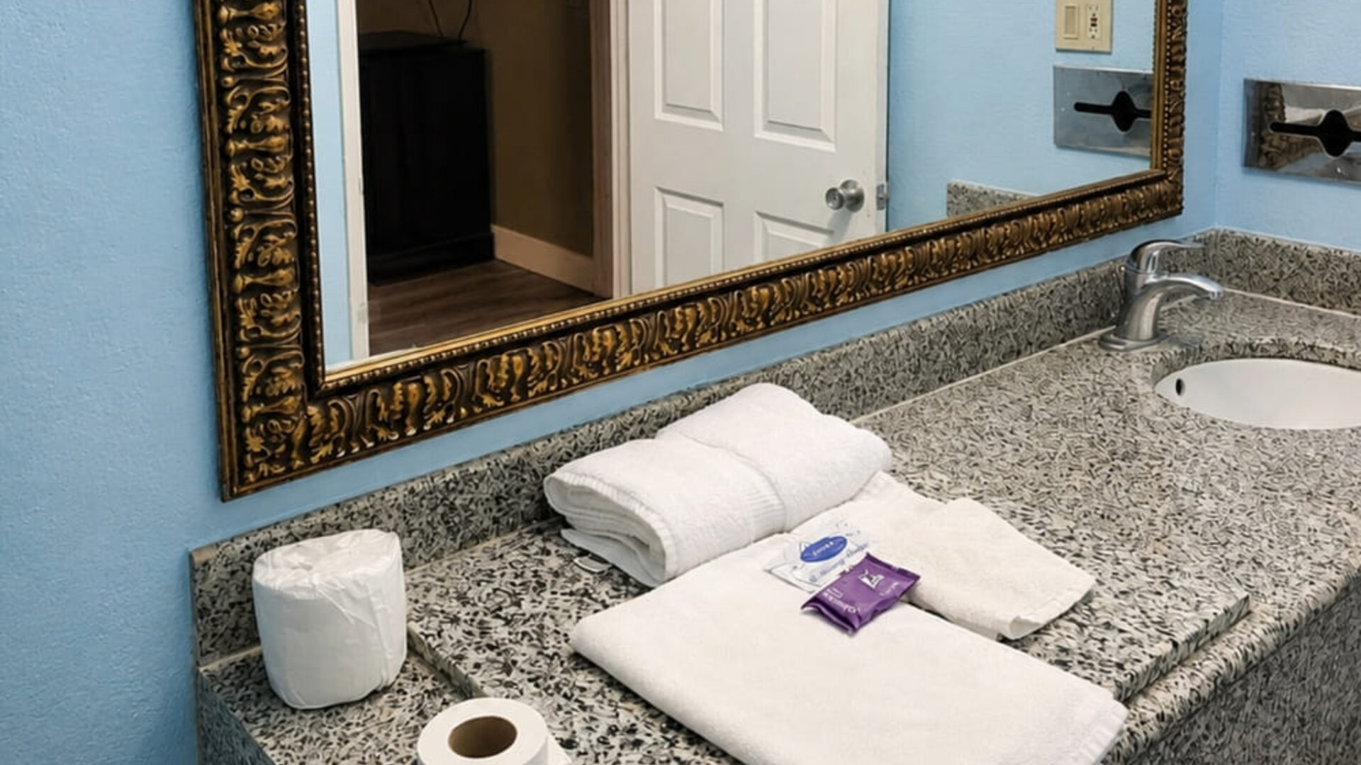 Guest bathroom vanity area featuring granite countertops, ample space, and essential amenities for a comfortable stay at Blue Way Inn & Suites Wichita East.