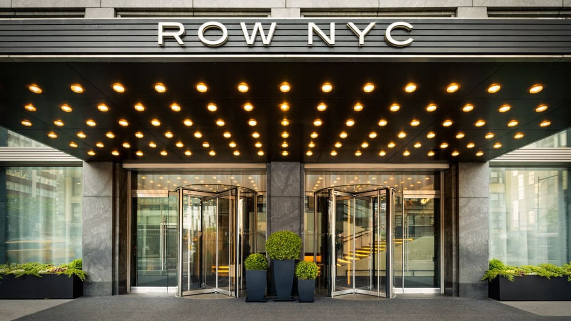 Close-up view of the iconic Row NYC entrance showcasing contemporary design, illuminated canopy lighting, and stylish curb appeal.
