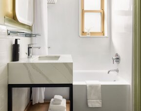 Guest bathroom featuring a spacious bathtub, modern vanity, and clean contemporary décor designed for comfort at Row NYC.