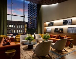 Sophisticated lobby lounge featuring floor-to-ceiling windows, contemporary furnishings, and comfortable gathering spaces at Row NYC.