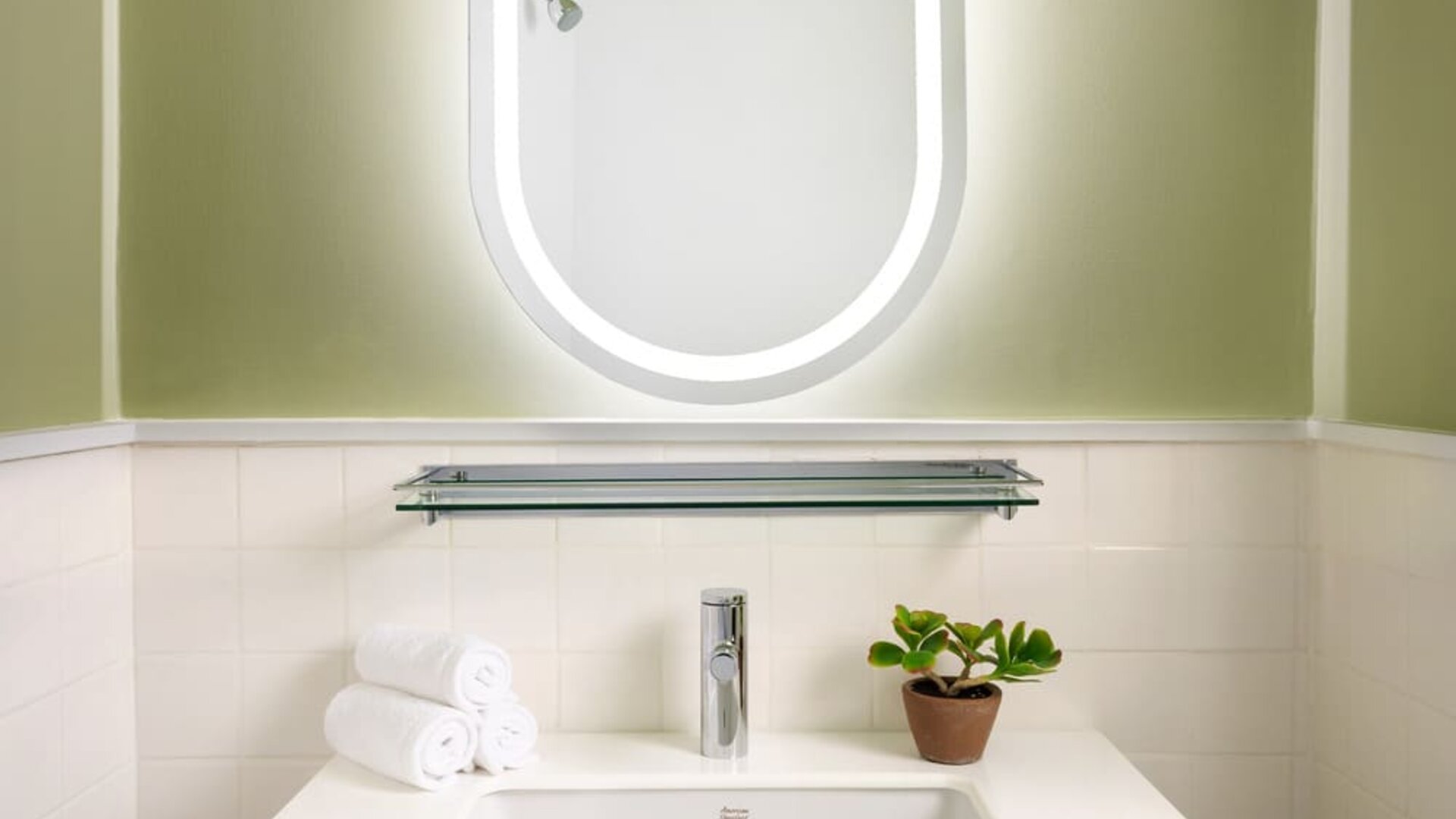 Contemporary vanity area featuring a stylish illuminated mirror, elegant sink, and modern design details at Row NYC.