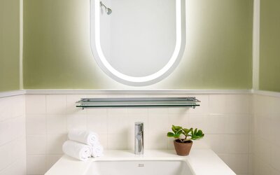 Contemporary vanity area featuring a stylish illuminated mirror, elegant sink, and modern design details at Row NYC.