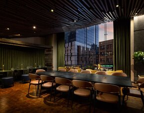 Stylish communal workspace and lounge area featuring large windows, contemporary furnishings, and flexible seating options at Row NYC.