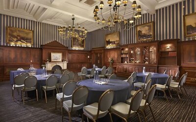 Elegant meeting room featuring round tables, chandeliers, and classic wood paneling at The Grand Brighton.