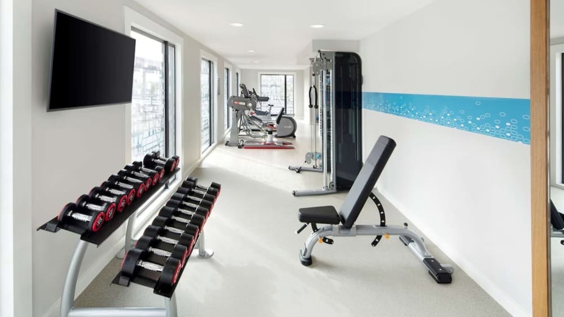 Bright fitness center with machines and equipment at the Hampton by Hilton London Docklands.