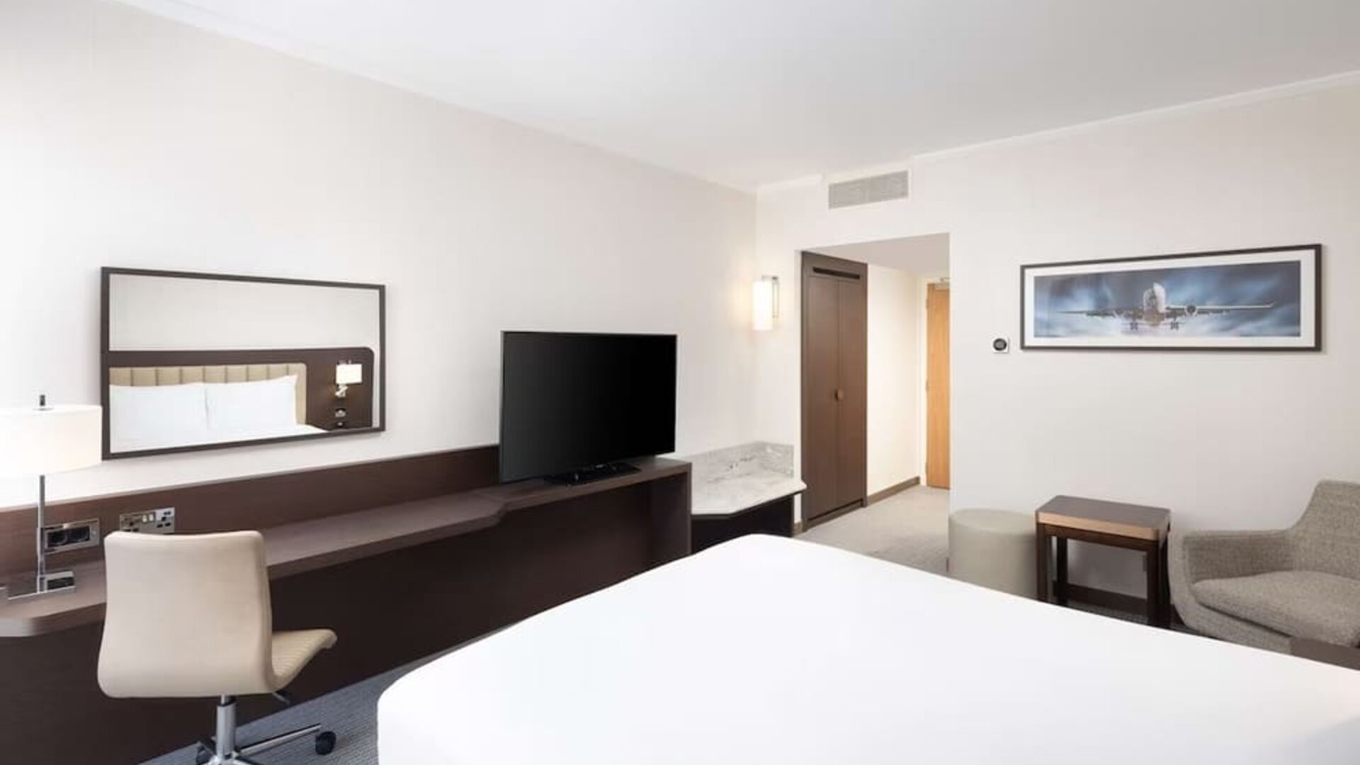 Bright king bedroom with sofa and desk at the Hilton London Gatwick Airport.