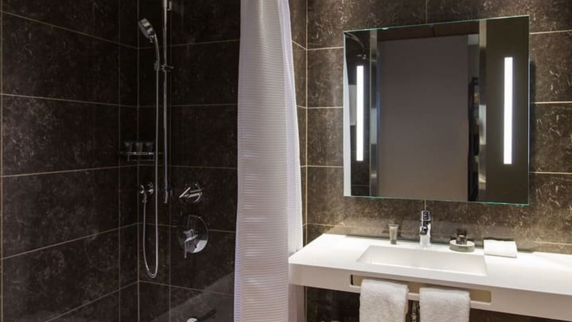Guest bathroom with shower and tub at AC Hotel Cincinnati At Liberty Center.