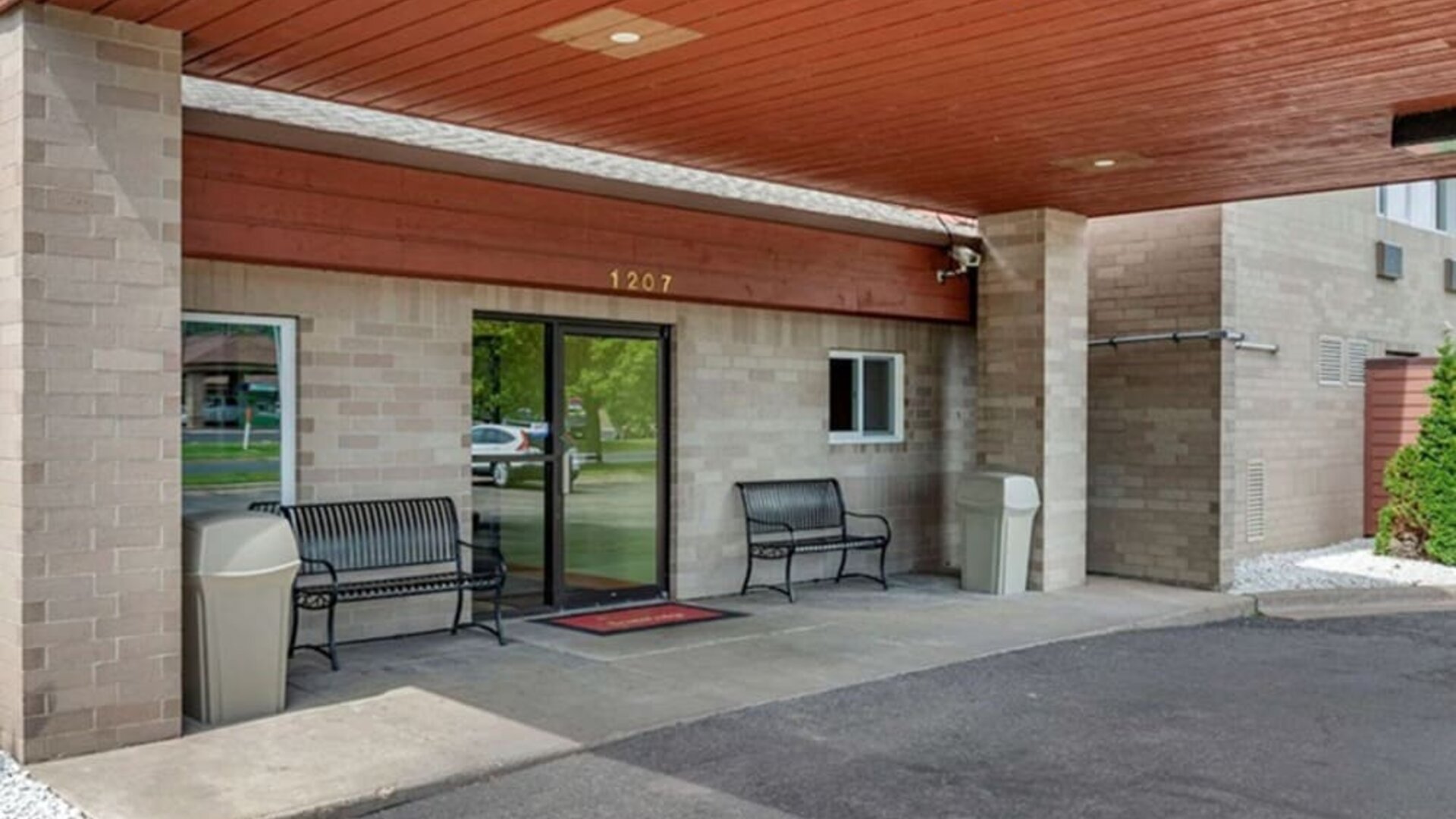 Outdoor seating and hotel entrance at Coratel Inn & Suites By Jasper River Falls.