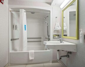 Accessible guest bathroom featuring a roll-in shower, support grab bars and modern vanity at Hampton Inn Ridgefield Park.