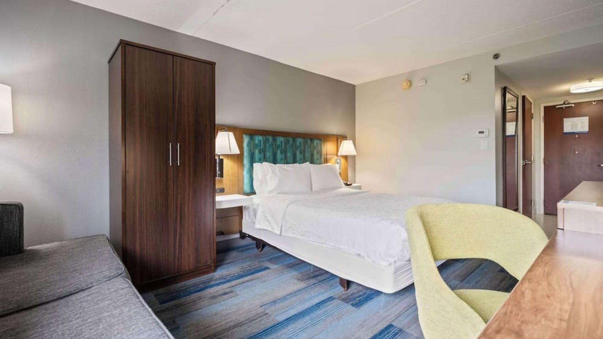 Spacious guest room featuring a plush king bed, ergonomic workspace, comfortable seating, and modern amenities for a relaxing stay at Hampton Inn Ridgefield Park.