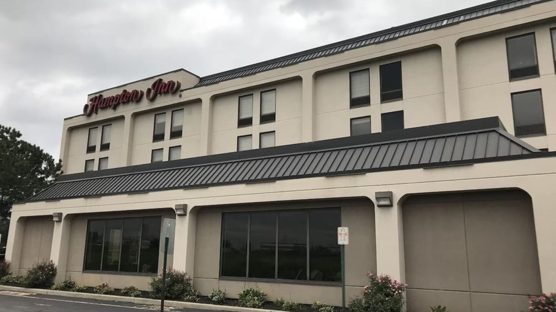Exterior entrance of Hampton Inn Ridgefield Park featuring a covered porte-cochère, landscaped grounds, and convenient guest parking.