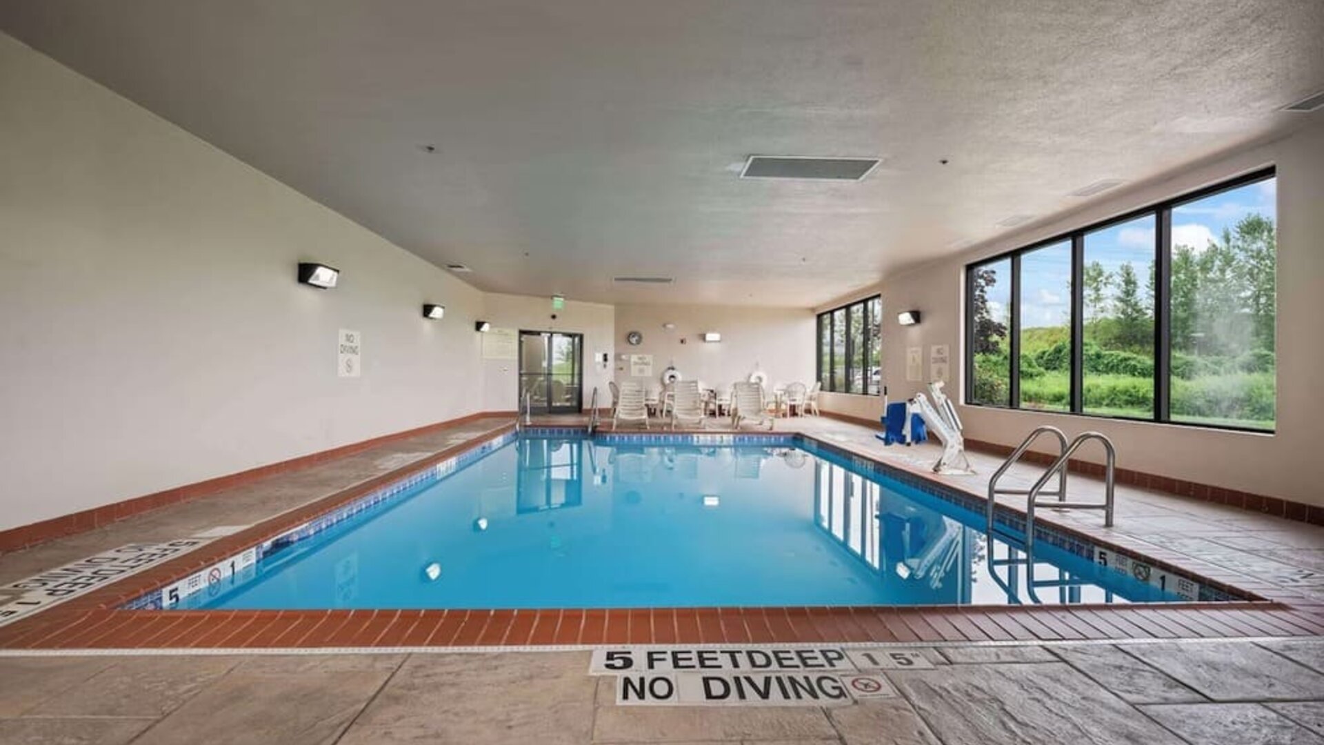 Spacious indoor pool offering a refreshing environment with ample natural light and comfortable seating for guests at Hampton Inn Ridgefield Park.