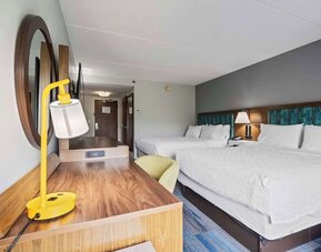 Double Queen guest room featuring two plush Hampton beds, a spacious work desk, comfortable seating, modern furnishings, and thoughtful amenities for a relaxing stay at Hampton Inn Ridgefield Park.