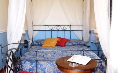 Romantic guest room with a wrought-iron canopy bed, hardwood flooring, and timeless décor.