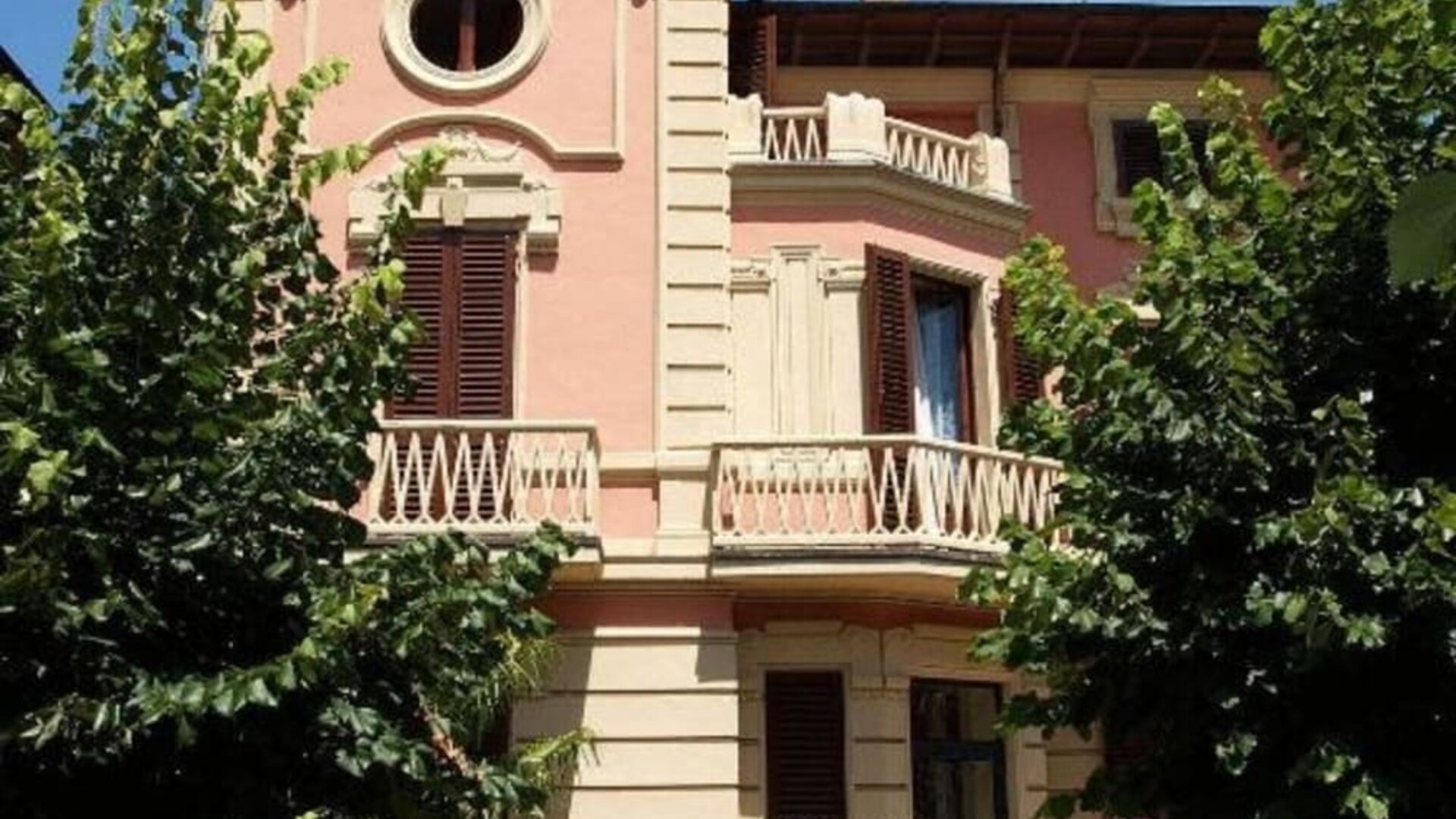 Exterior view of Petit Chateau highlighting its historic villa design surrounded by mature trees and gardens.