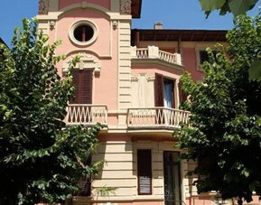 Exterior view of Petit Chateau highlighting its historic villa design surrounded by mature trees and gardens.