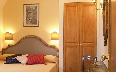 Bright and elegant guest room featuring a comfortable double bed, classic furnishings, and a writing desk.