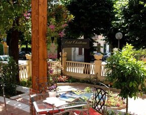 Peaceful outdoor terrace with garden seating surrounded by lush greenery, perfect for enjoying breakfast or relaxing outdoors.