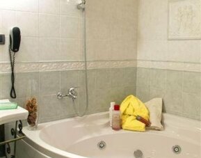 Spacious bathroom with a whirlpool bathtub, overhead shower, and elegant tiled finishes for a relaxing stay.