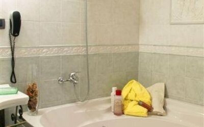Spacious bathroom with a whirlpool bathtub, overhead shower, and elegant tiled finishes for a relaxing stay.