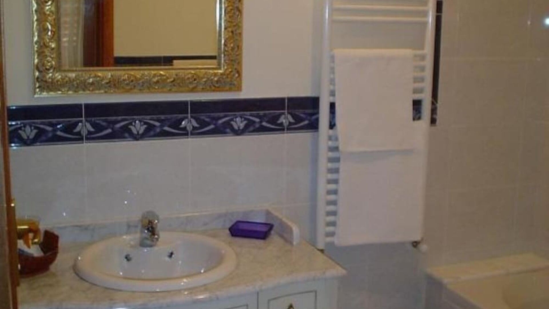 Elegant bathroom featuring a marble vanity, bathtub with shower, bidet, heated towel rail, and ornate mirror.