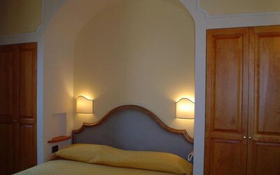 Cozy guest room with a double bed, upholstered headboard, built-in wardrobe, and warm ambient lighting.