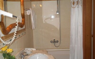 Bright bathroom with a marble vanity, bathtub with shower, hairdryer, and complimentary toiletries.