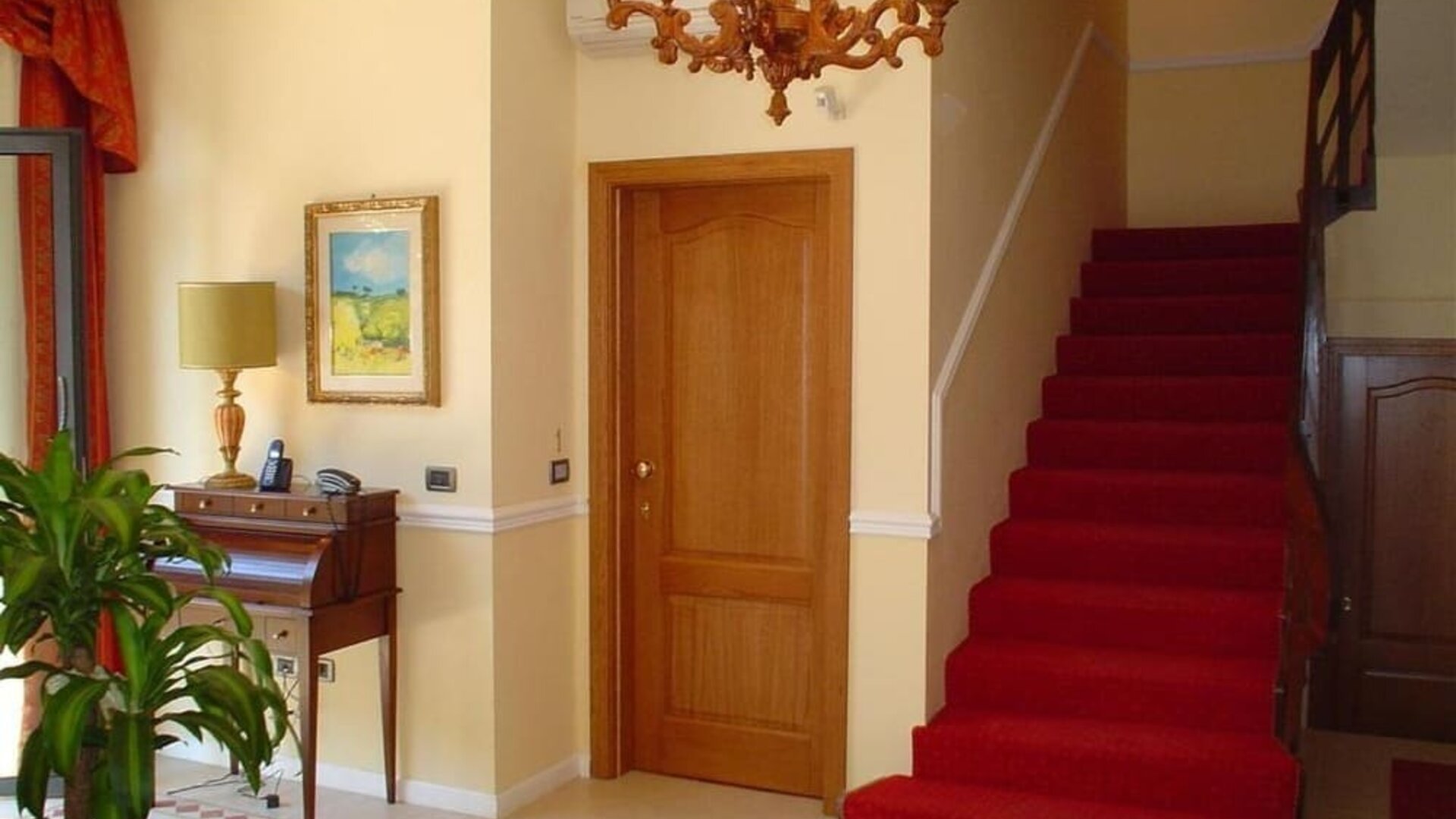 Elegant hotel lobby featuring classic furnishings, a grand staircase, chandelier lighting, and a welcoming atmosphere.