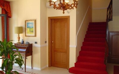 Elegant hotel lobby featuring classic furnishings, a grand staircase, chandelier lighting, and a welcoming atmosphere.