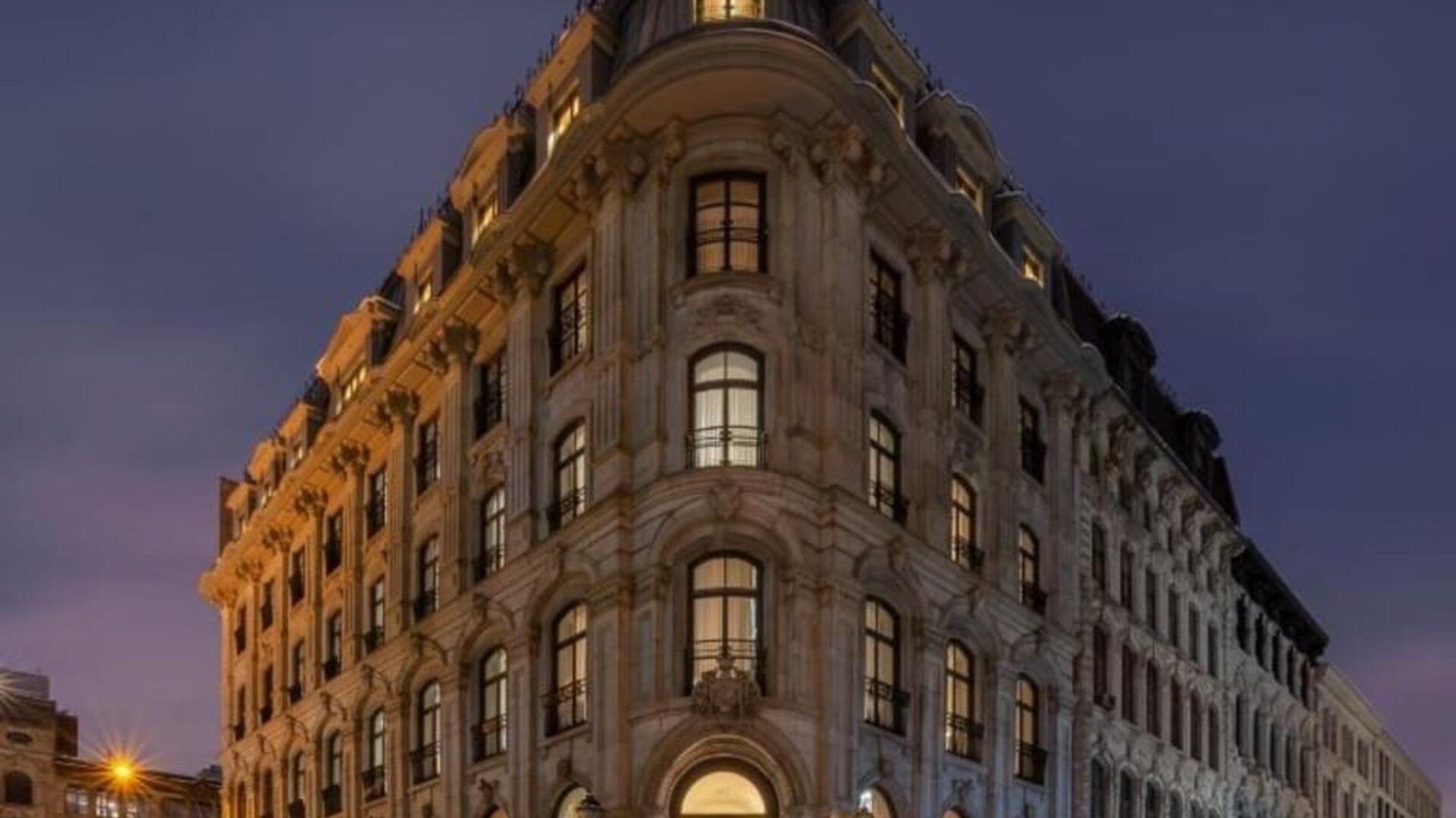 Historic stone hotel exterior illuminated at night on a corner street with arched entrance and tall windows. Hotel Gault.