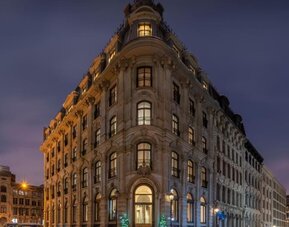 Historic stone hotel exterior illuminated at night on a corner street with arched entrance and tall windows. Hotel Gault.
