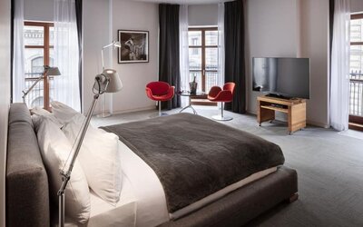 Spacious king guest room with large windows, red accent chairs, seating area, and flat-screen television. Hotel Gault.