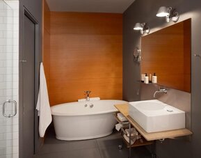 Contemporary bathroom with freestanding bathtub, floating sink, large mirror, and glass-enclosed shower. Hotel Gault.