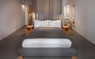 Minimalist guest room with platform king bed, bedside tables, and open bathroom entrance with modern fixtures. Hotel Gault.