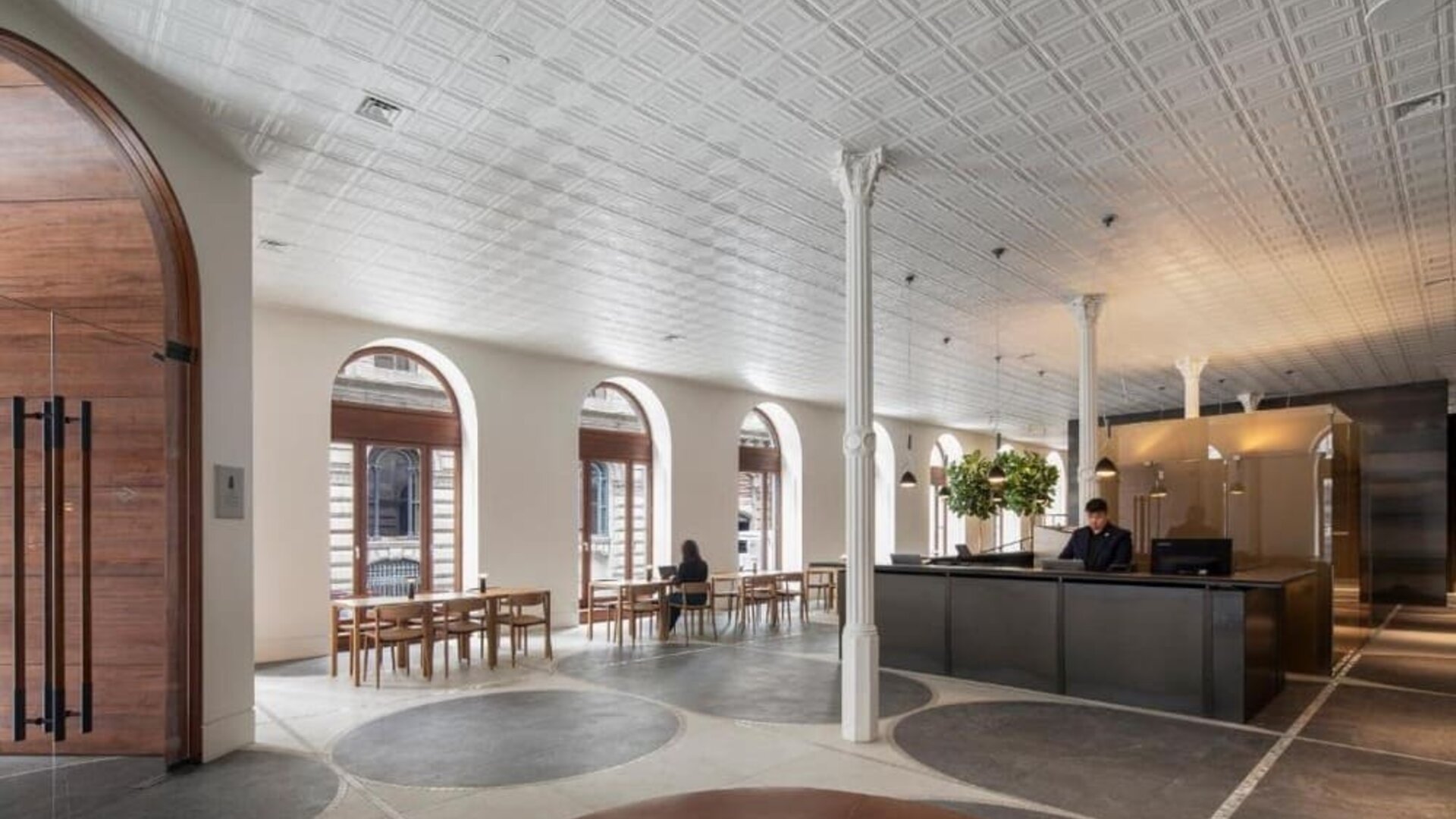 Spacious hotel lobby with reception desk, arched windows, dining tables, and contemporary seating areas. Hotel Gault.