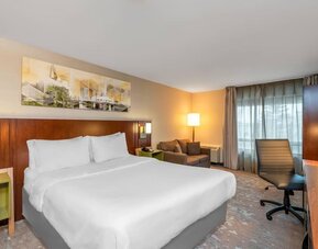 King guest room with work desk, sofa, large window, and contemporary décor at Comfort Inn Boucherville.
