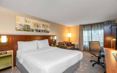 King guest room with work desk, sofa, large window, and contemporary décor at Comfort Inn Boucherville.