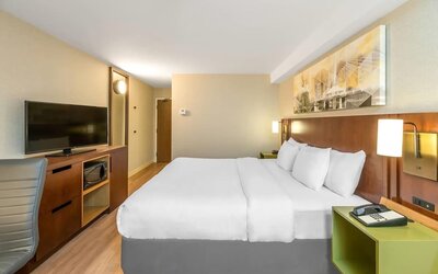 King guest room with work desk, flat-screen TV, microwave, and contemporary furnishings at Comfort Inn Boucherville.