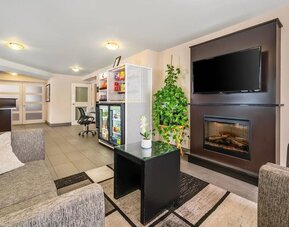 Hotel lobby with fireplace, flat-screen TV, snack market, and comfortable lounge seating at Comfort Inn Boucherville.
