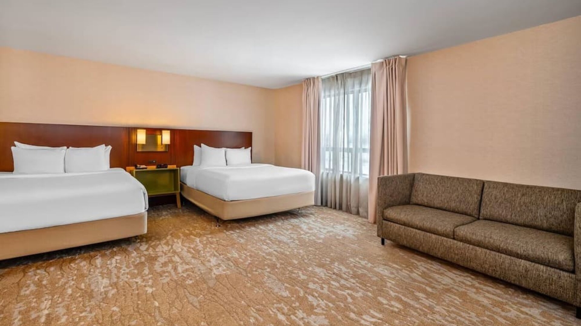 Spacious guest room with two queen beds, sofa, large window, and open floor layout at Comfort Inn Boucherville.