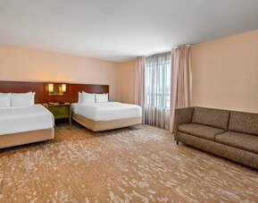 Spacious guest room with two queen beds, sofa, large window, and open floor layout at Comfort Inn Boucherville.
